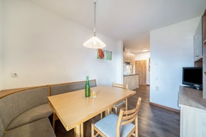 Un comedor con mesa de madera, banco acolchado y una lámpara colgante.