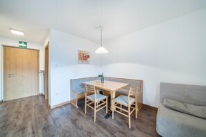 Ett rum med ett träbord, fyra stolar, en soffa, en taklampa och en dörr.