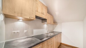 Een keuken met houten kastjes, een zwart aanrecht en een roestvrijstalen spoelbak.