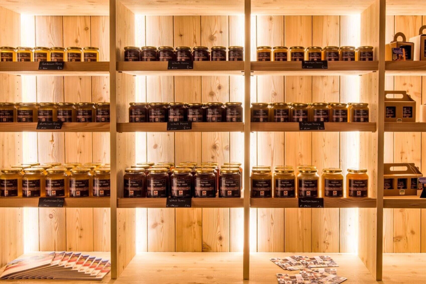 Un interno in legno con scaffali che espongono barattoli di miele e favi.