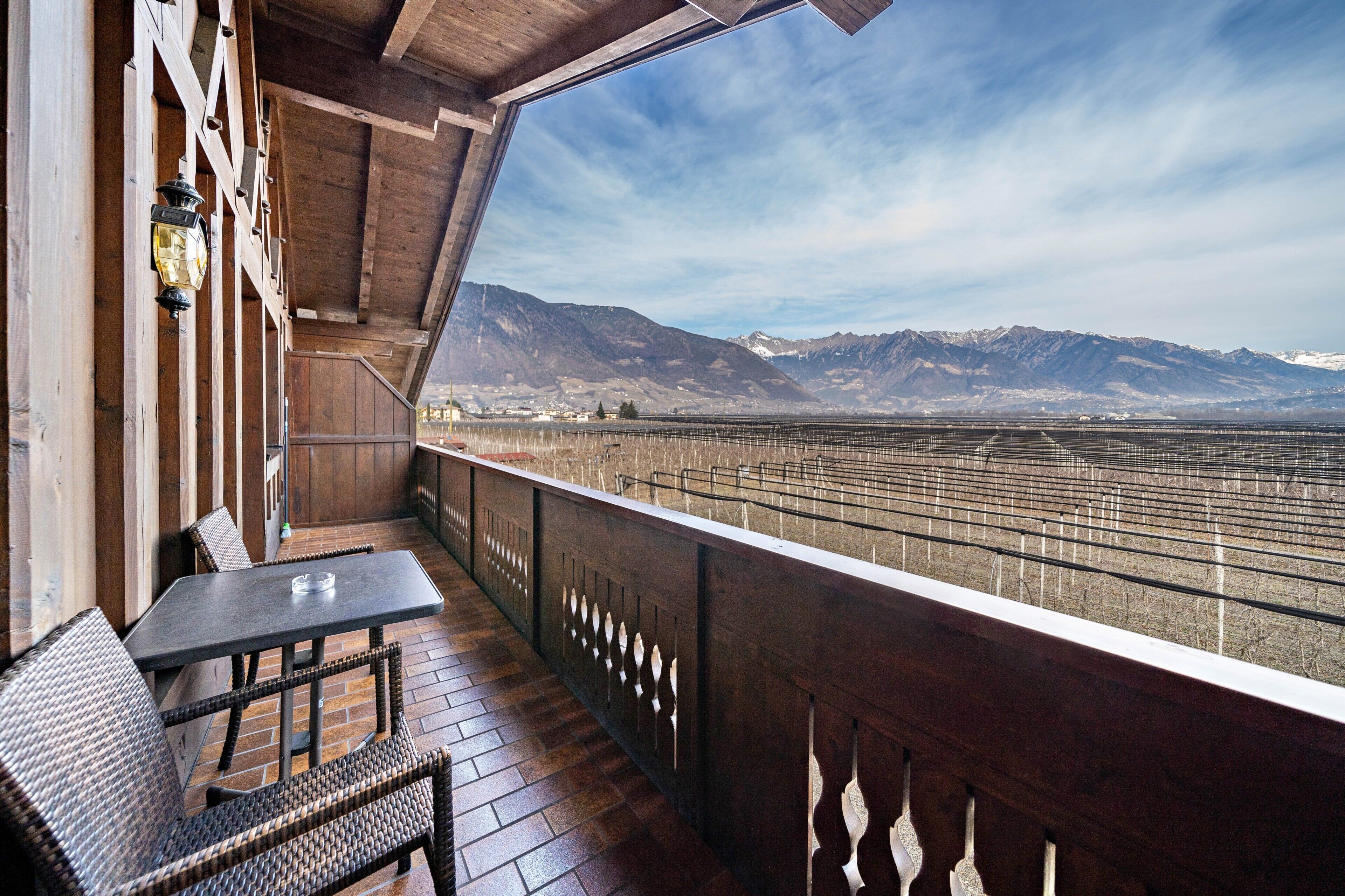 Ein Balkon mit Blick auf Berge, einem Tisch und Korbstühlen.