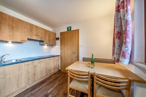 A kitchen with wooden cabinets, a sink, and a dining table with chairs.