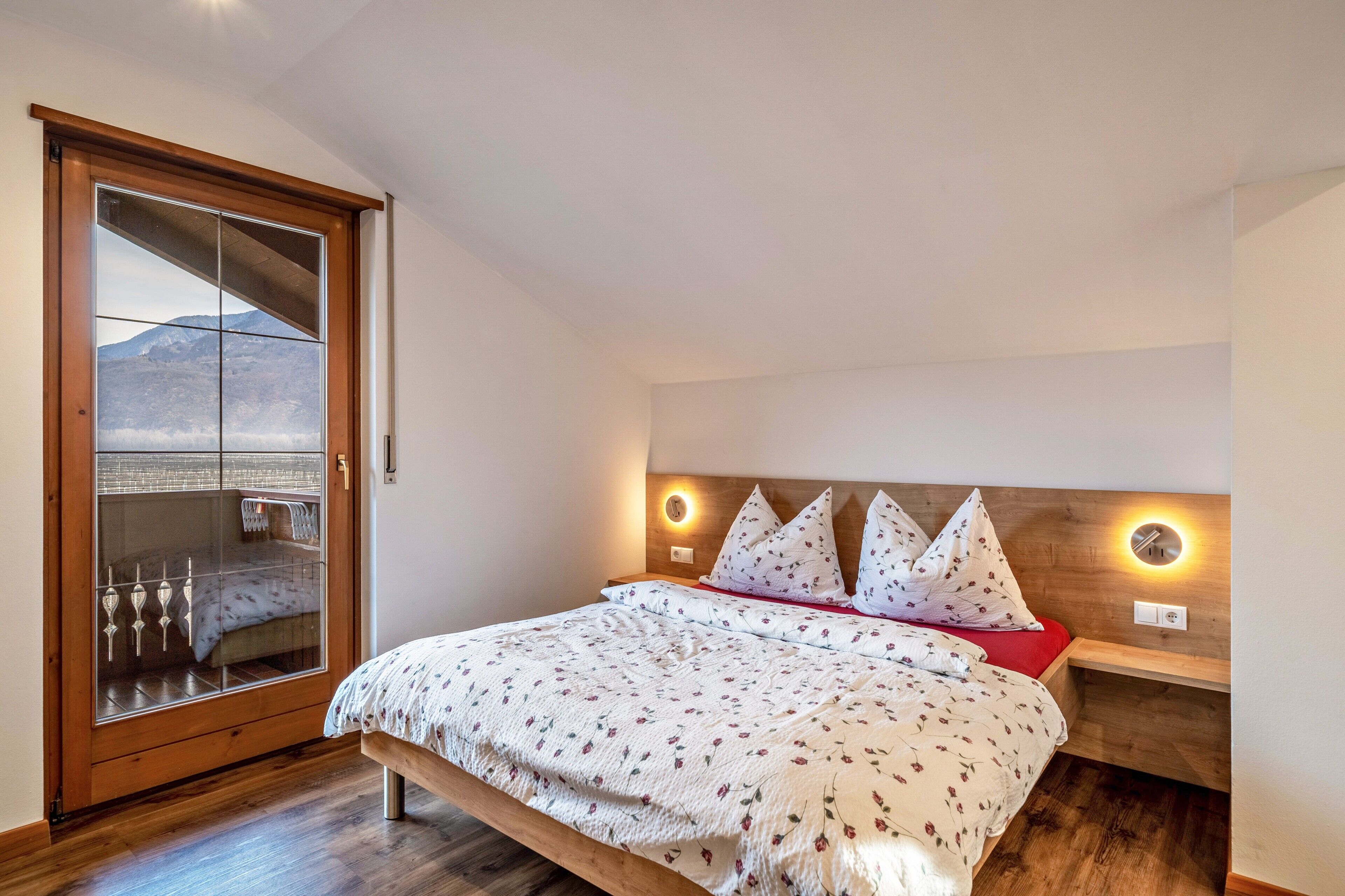 Ein Schlafzimmer mit einem Bett, einem Holzkopfteil, Nachttischen und einem großen Fenster mit Blick.