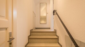 Una scala con corrimano, una porta e uno specchio che riflette il corridoio.