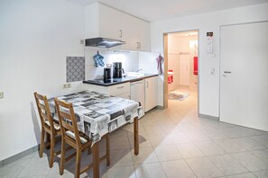 A compact kitchen with a dining table, chairs, and a coffee maker.