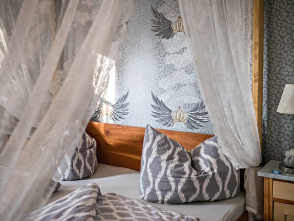 A bed with a canopy, patterned pillows, and a wall with a decorative emblem.