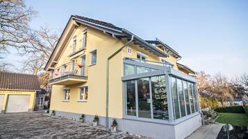 Ein zweistöckiges Haus mit Balkon, Garage und Wintergarten.