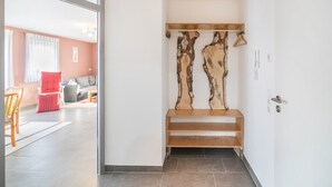 Ein Flur mit einer Bank, einem Holzbilde an der Wand und einer Tür.