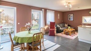 Ein Wohnzimmer mit Esstisch, Stühlen, einer Couch, einem Couchtisch und einem kleinen Schrank.