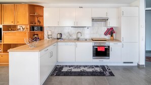 Eine moderne Küche mit weißen Schränken, einem Backofen, einer Mikrowelle und einer Kaffeemaschine.