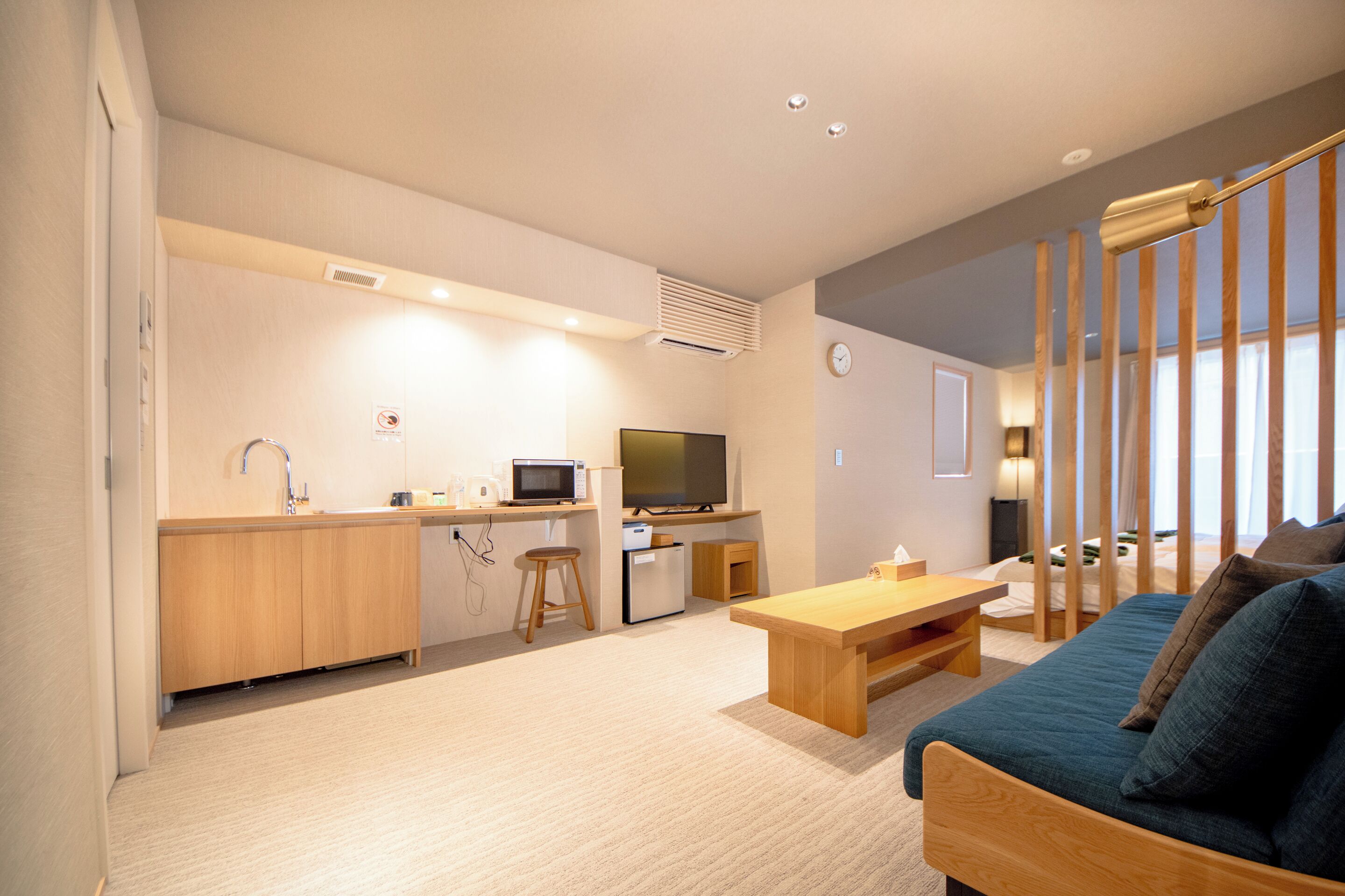 Un espacio habitable pequeño con kitchenette, televisión, sofá y mesa de comedor de madera.