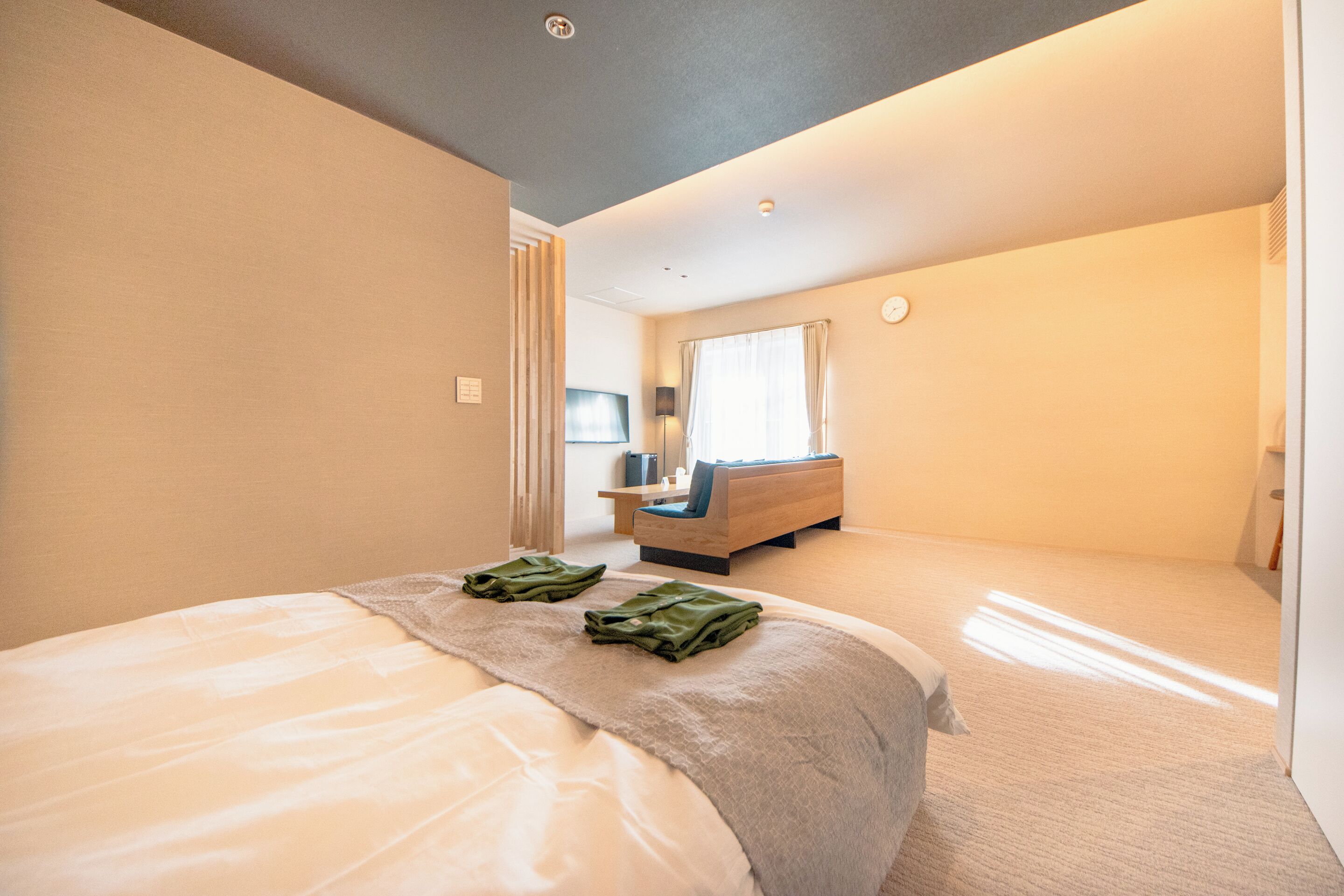 A modern hotel room with a large bed, a desk, and a view of the city.