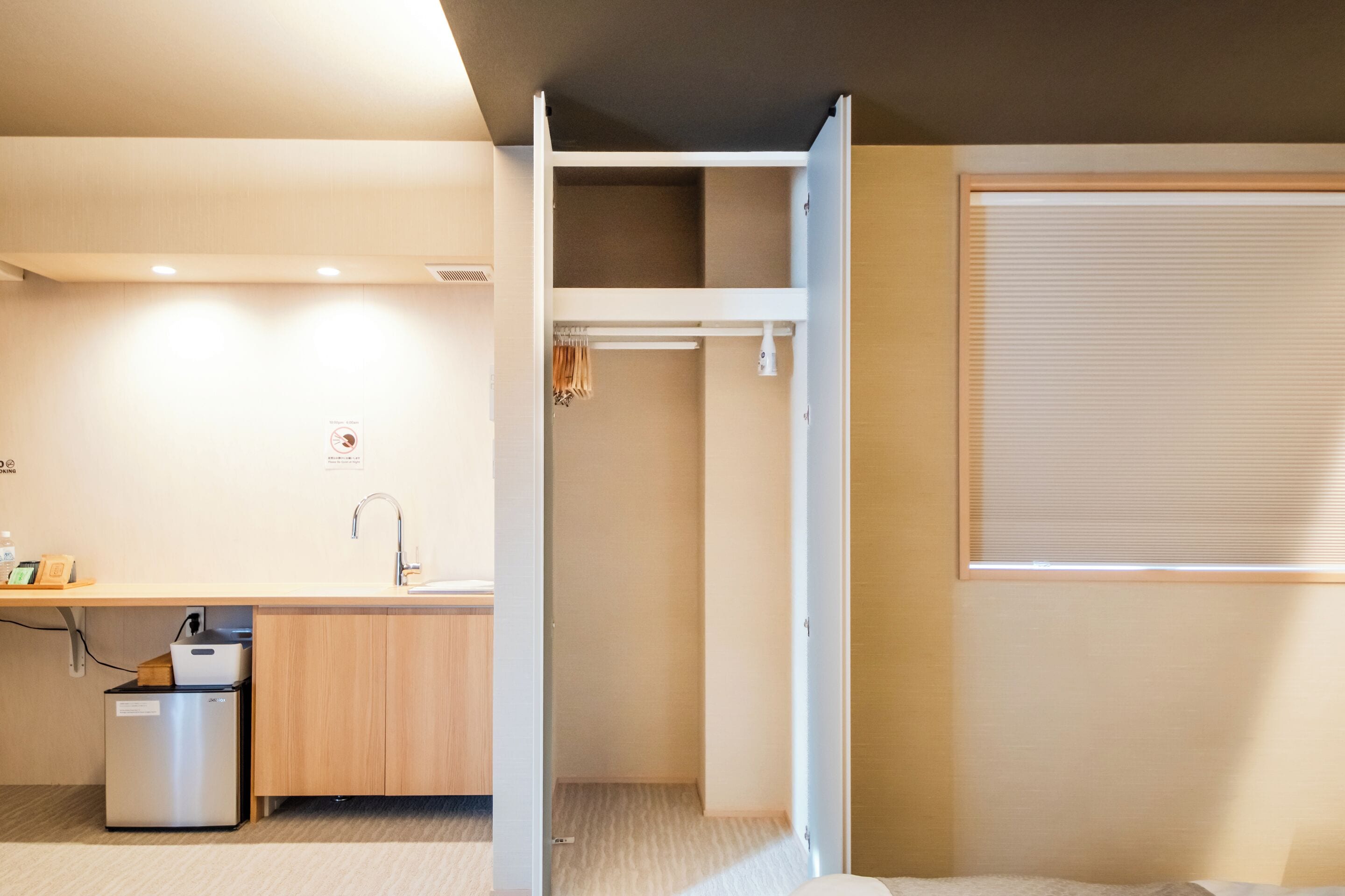 A compact hotel room with a kitchenette, a small bathroom, and a sliding door closet.