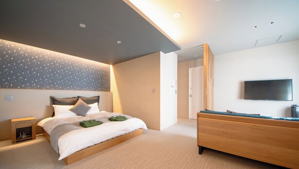 A modern bedroom with a bed, bedside table, and a TV mounted on the wall. - Hotel Rokune (Nara)
