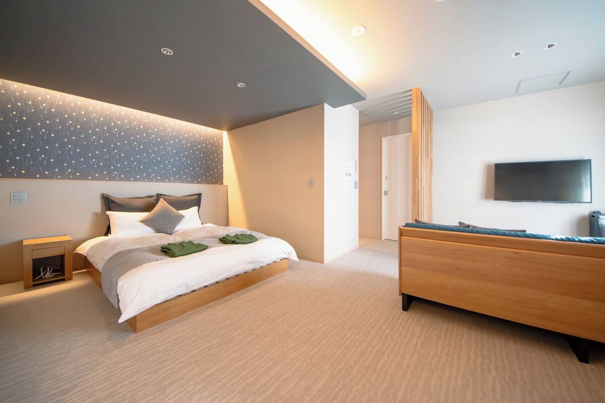 A modern bedroom with a bed, bedside table, and a TV mounted on the wall.