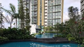 A swimming pool surrounded by lush greenery and tall buildings in the background. - The Elysia Park Residence (Iskandar Puteri)