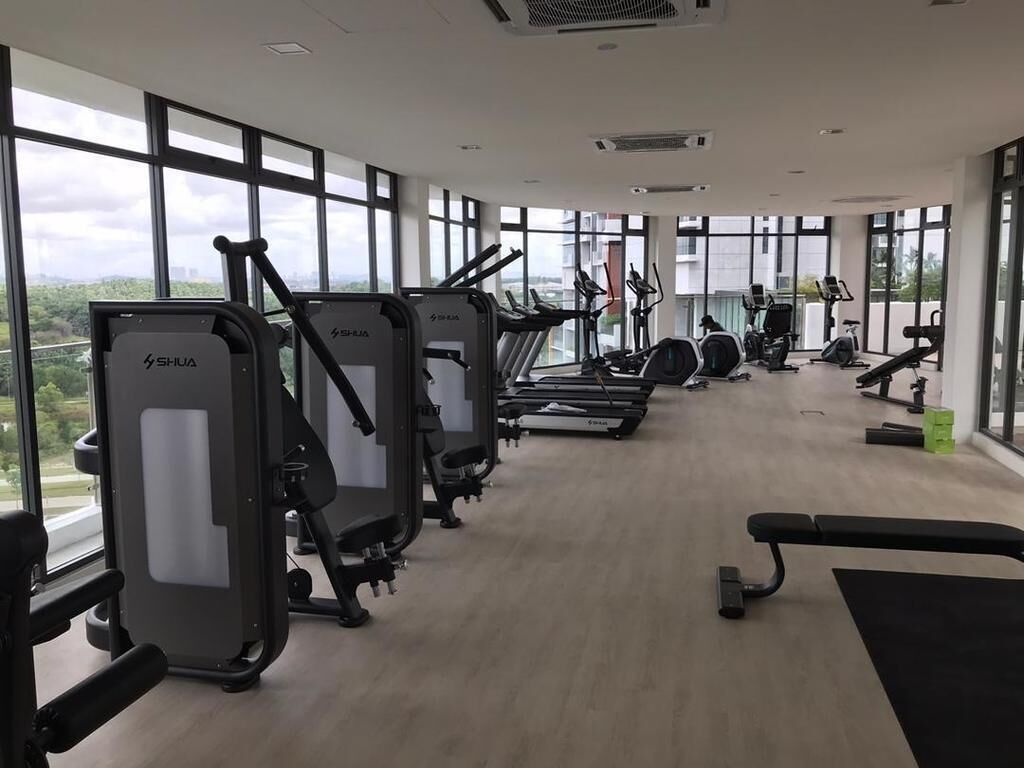 A gym with various exercise equipment, large windows, and a view of the city.