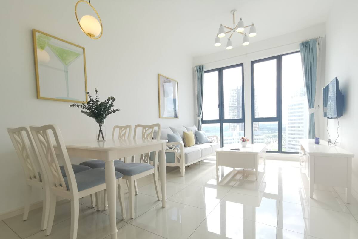 Un salon moderne avec un coin repas, de grandes fenêtres et une vue sur la ville.