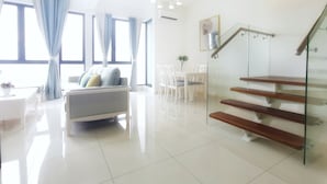 A modern living room with a sofa, dining area, and a staircase. - The Elysia Park Residence (Iskandar Puteri)