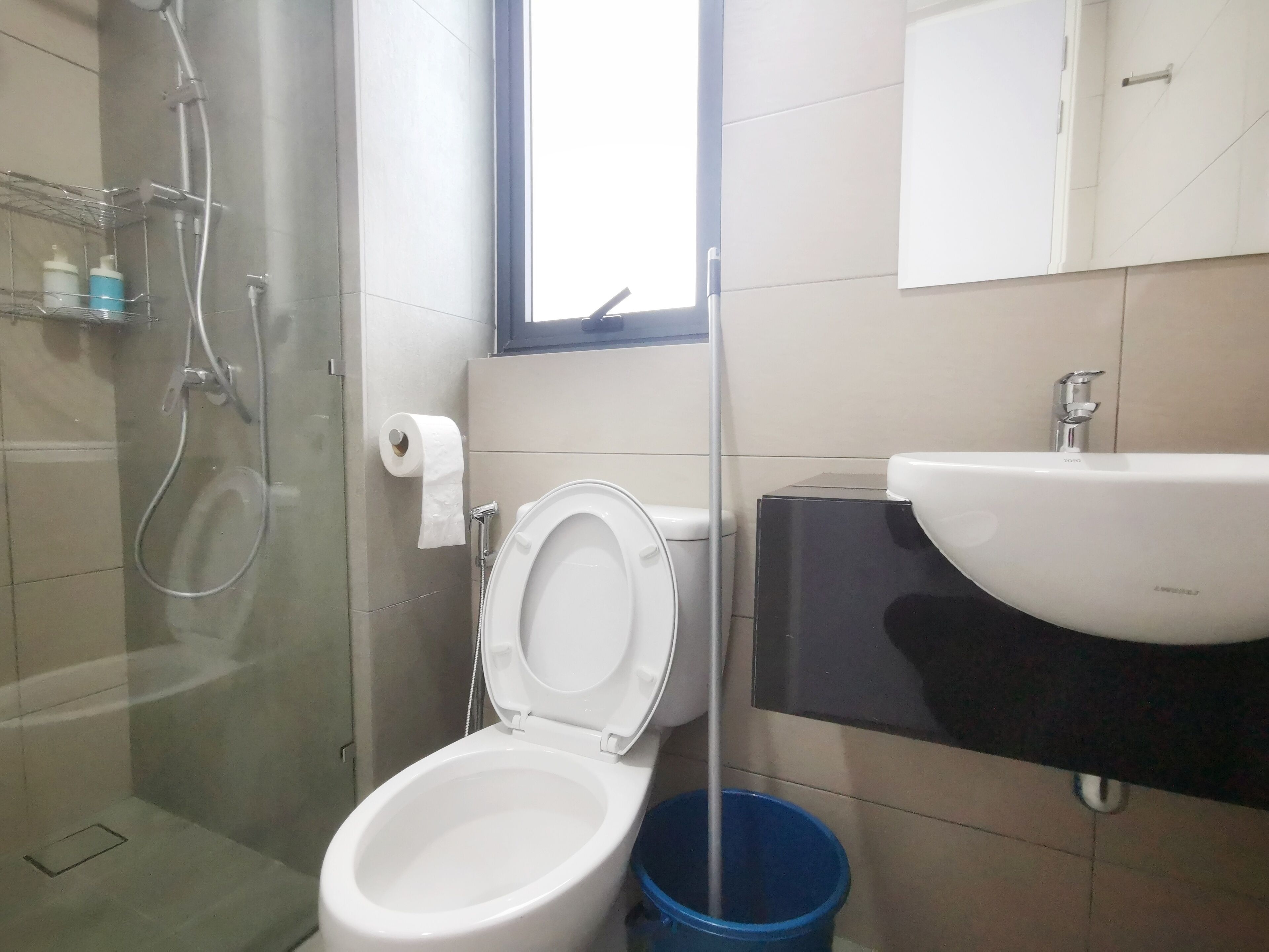 Un baño con inodoro, lavamanos, ducha y ventana.