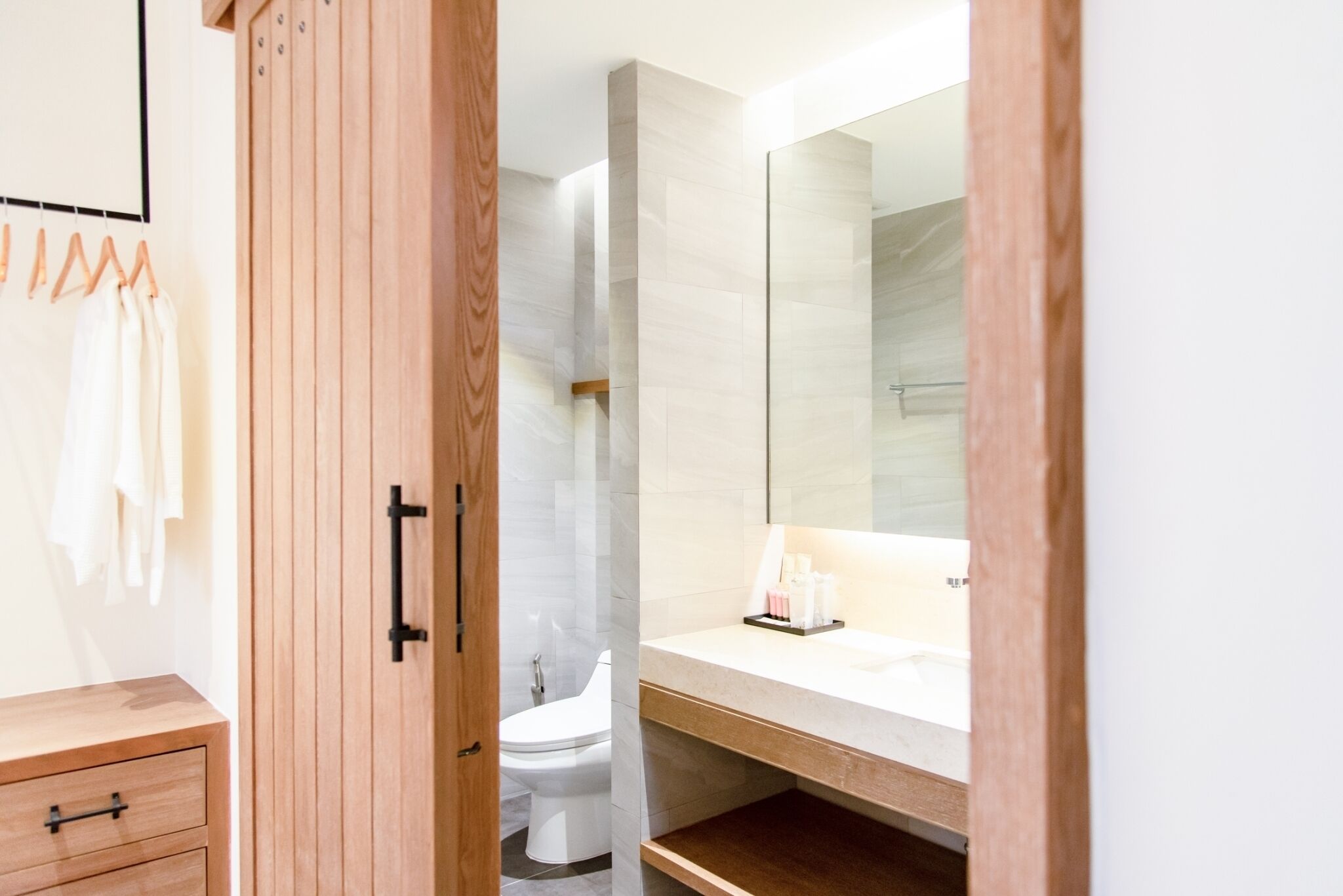 Une salle de bain moderne avec un meuble-lavabo en bois, un grand miroir et un espace douche.