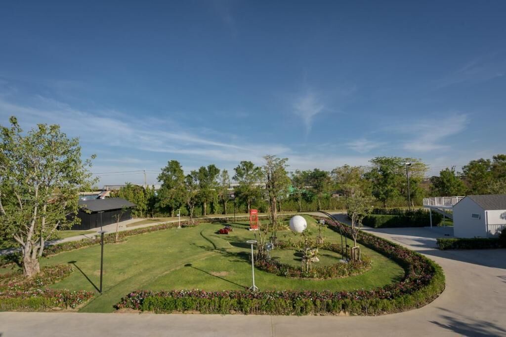 A residential area with a well-maintained lawn, a spherical sculpture, and a white building.