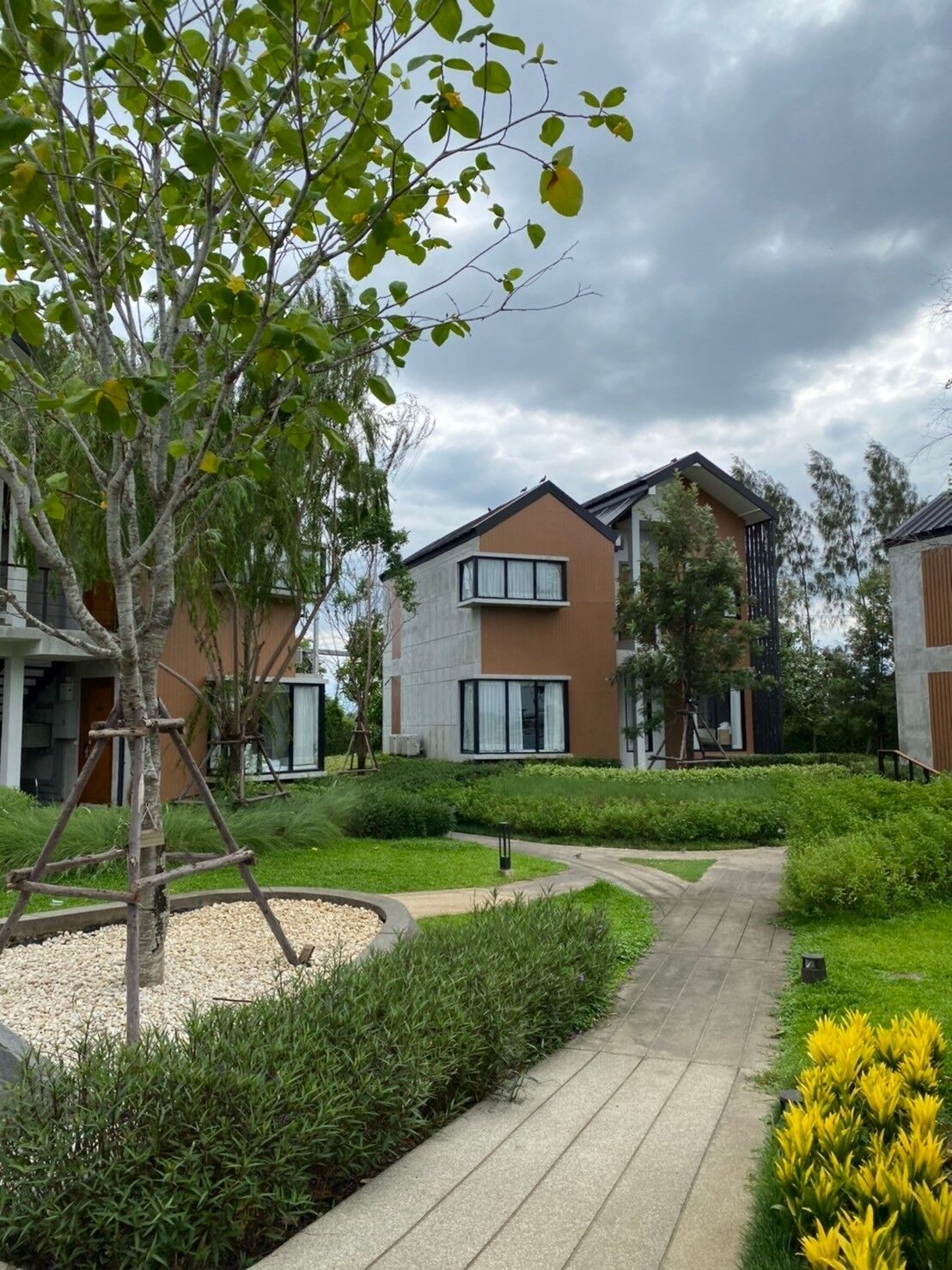 Een modern woongebouw met een pad naar de ingang, omgeven door verzorgde beplanting en een heldere lucht.