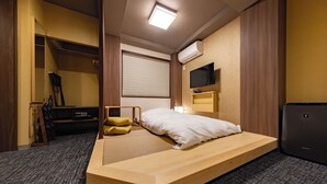 A compact hotel room with a bed, a wardrobe, a television, and an air conditioning unit. - MADOKA Kyoto Station West (Kyoto)