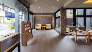 A modern hotel lobby with a reception desk, seating area, and large windows. - MADOKA Kyoto Station West (Kyoto)