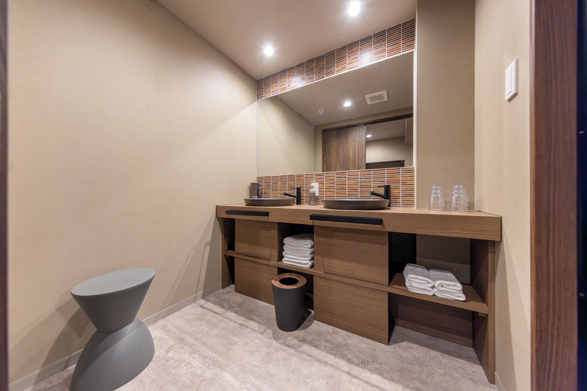 Un baño moderno con tocador de madera, un espejo grande y un perchero para toallas.