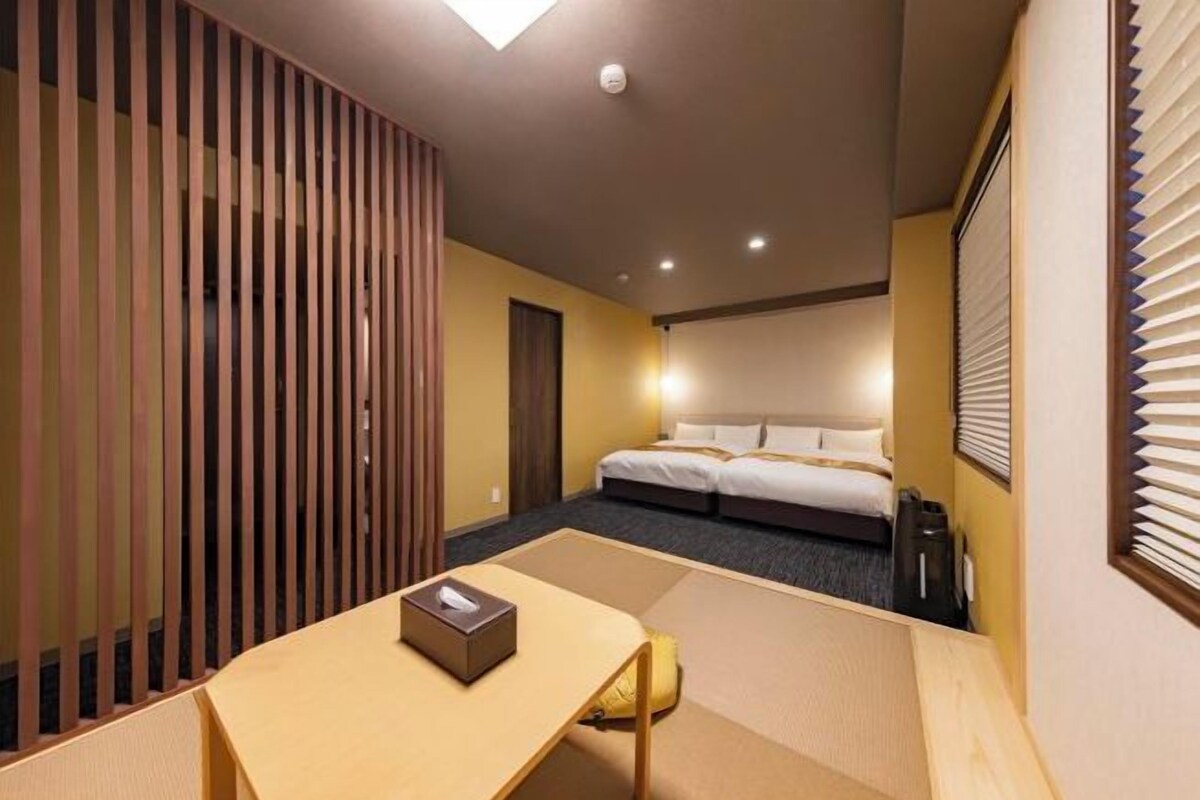 A hotel room with a bed, a desk, a chair, and a sliding door.