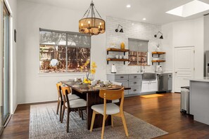 A modern kitchen with white brick backsplash, wooden cabinets, and a dining area with a wooden table and chairs. - Stunning Views, Patio, Beautiful Contemporary Home! (Sedona)