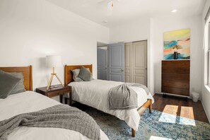 A bedroom with two beds, a nightstand, a lamp, a painting, and a wardrobe. - Stunning Views, Patio, Beautiful Contemporary Home! (Sedona)