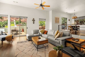A modern living room with a grey sofa, a coffee table, and a dining area with a table and chairs.