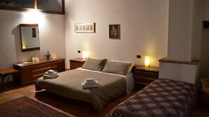 Un dormitorio con una cama grande, mesitas de noche, un tocador, un espejo y un pequeño sofá.
