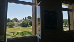 Una habitación con un ventanal que da a un espacio verde y edificios.