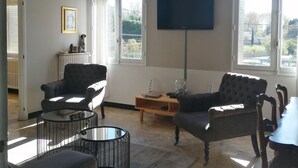 Un salón espacioso con techo alto, una lámpara moderna y amplios ventanales con vistas al exterior.