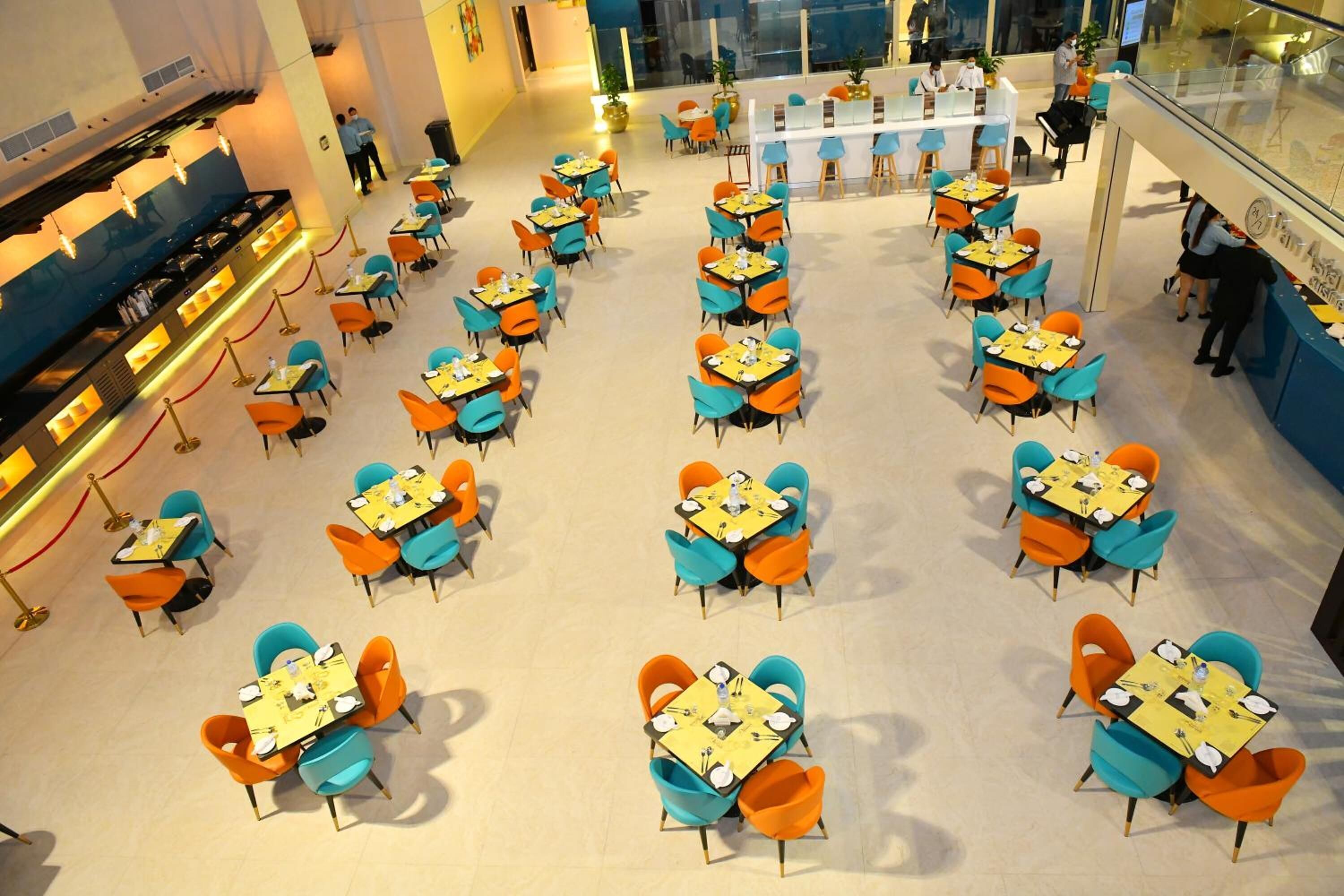 A spacious indoor dining area with multiple tables and chairs, a counter with a menu, and a glass railing overlooking the space.