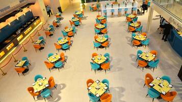 A spacious indoor dining area with multiple tables and chairs, a counter with a menu, and a glass railing overlooking the space.