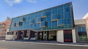Un hotel moderno con fachada de vidrio, identificado como "Fortune Atrium Hotel", y un restaurante "Friedy's" en la planta baja.