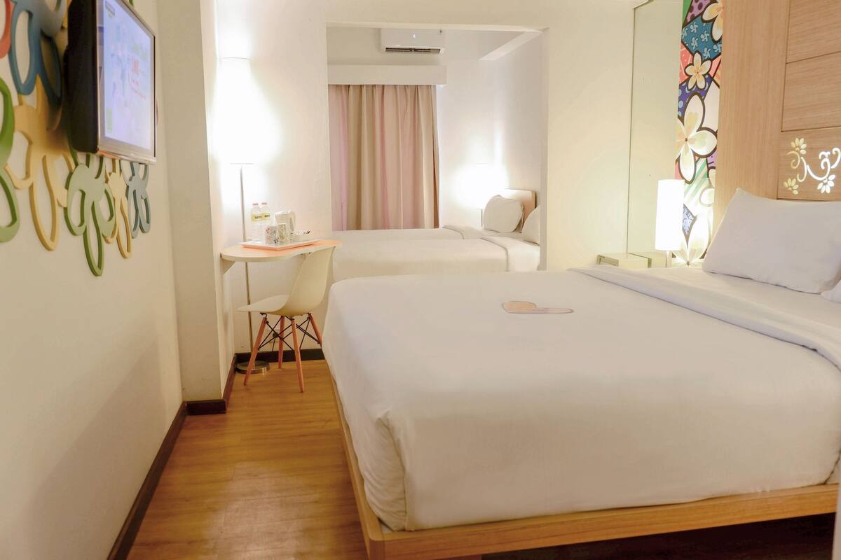 Una habitación de hotel con una cama, un escritorio, una silla y un televisor fijado en la pared.