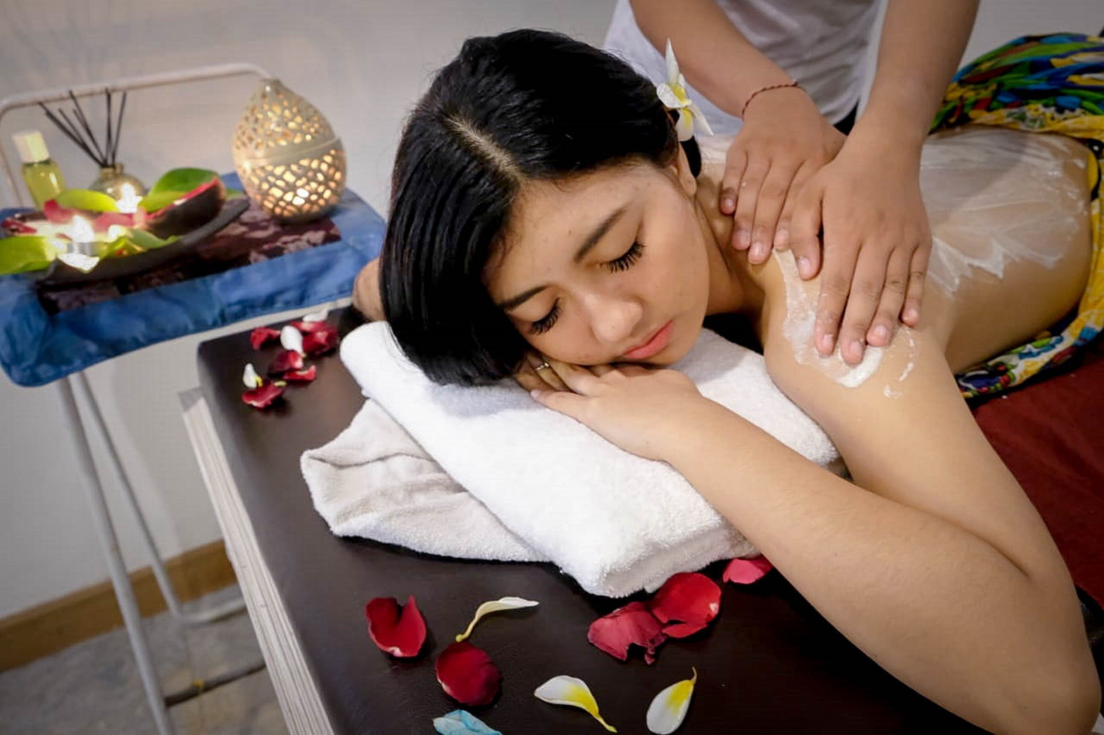 Une personne reçoit un massage sur lequel sont disposés des pétales de rose.