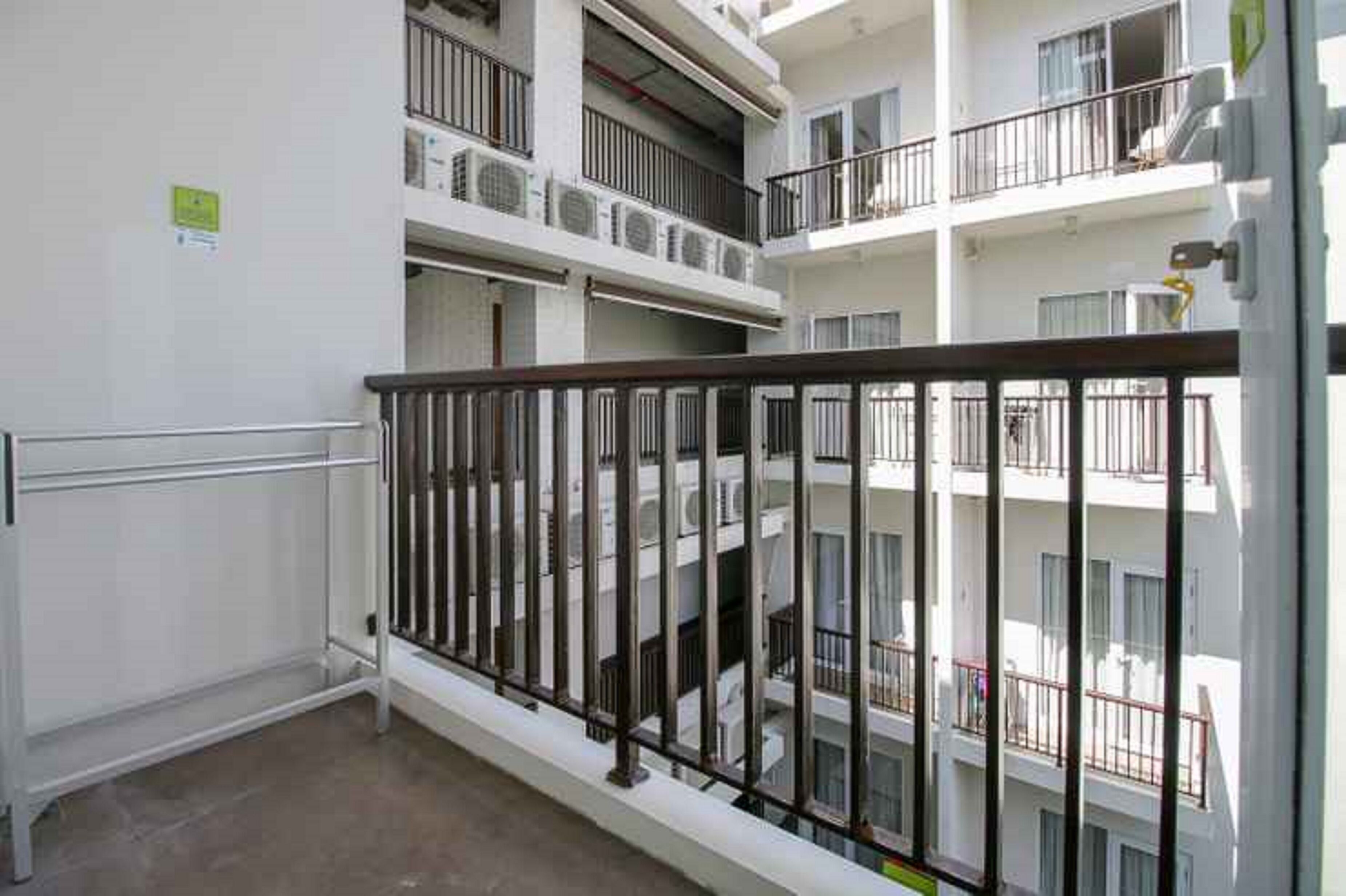 A multi-story residential building with balconies, railings, and air conditioning units.
