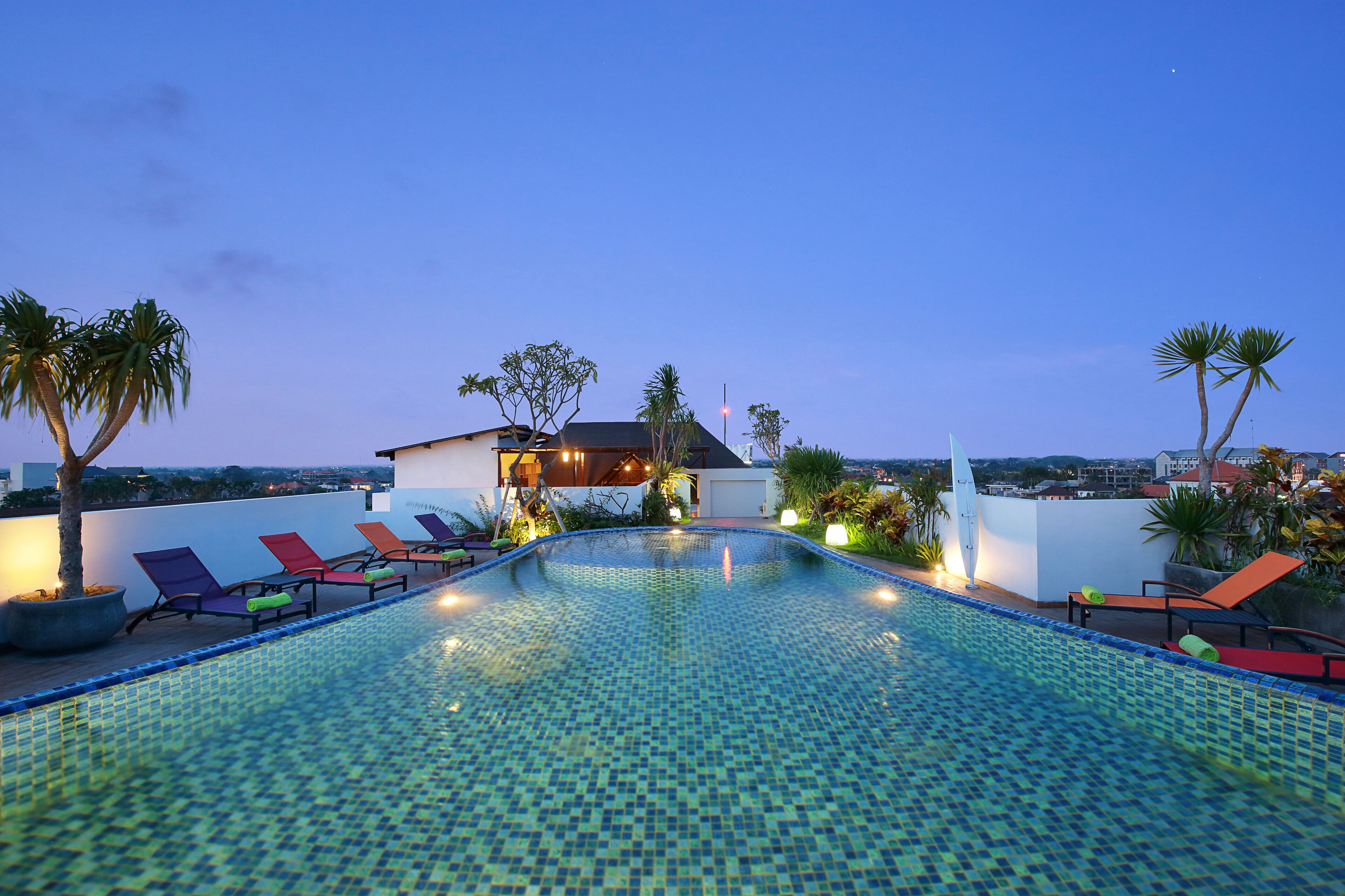 Ein Pool auf dem Dach mit Liegestühlen und Palmen.