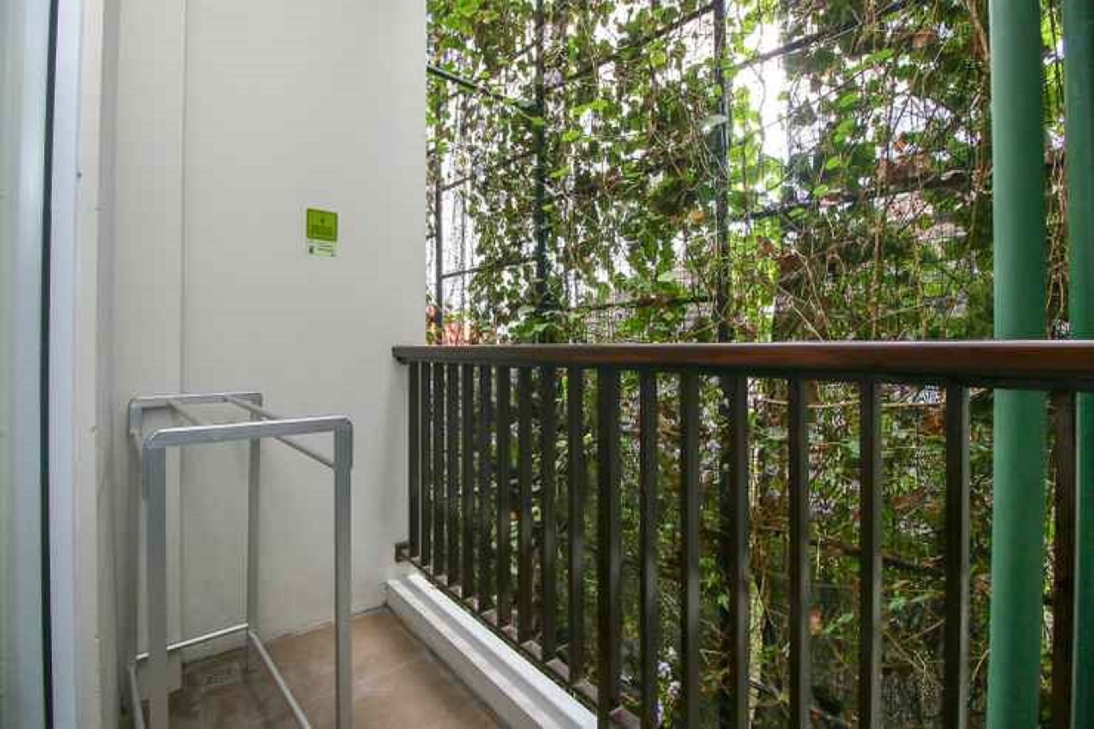 A balcony with a metal railing, a green pillar, and a white wall.