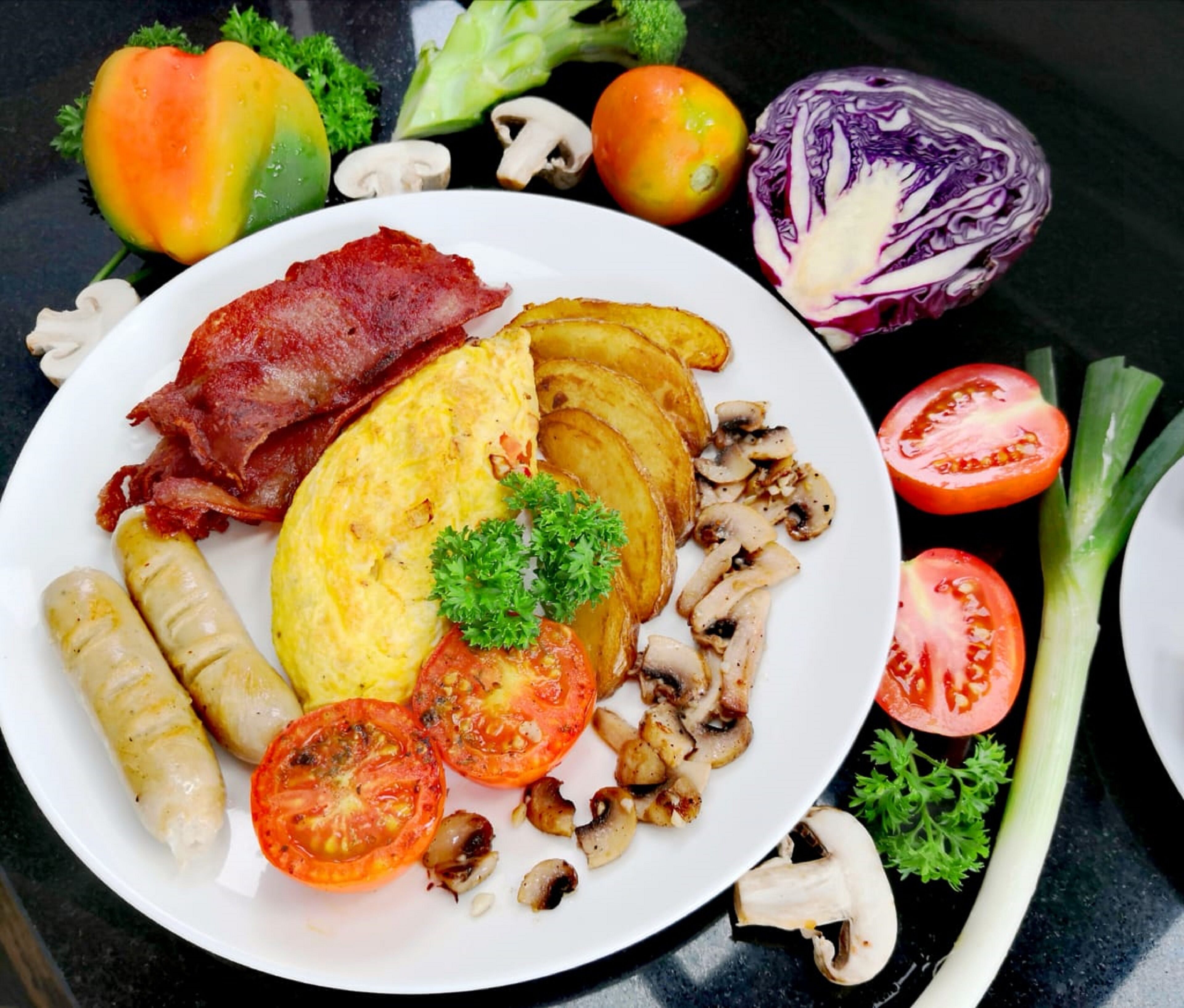 Un plato de comida con tocino, huevos, champiñones y tomates.