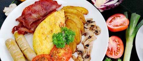Un plato de comida con tocino, huevos, champiñones y tomates.
