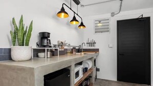 Eine Küche mit Arbeitsplatte, einer Kaffeemaschine, einem Spülbecken und einem Blumentopf.
