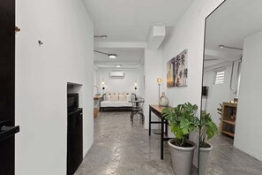 A hallway leading to a bedroom with a bed, bedside table, and potted plant. - Conveniently Located: 4 Suites Loiza & Beach Walk (San Juan)