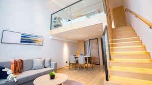 A modern apartment with a loft bedroom, a dining area, and a staircase.